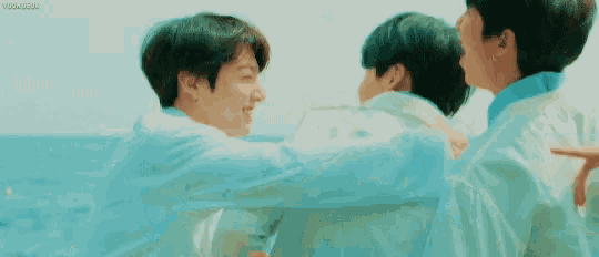 a group of young men are hugging each other while standing next to each other on a beach .