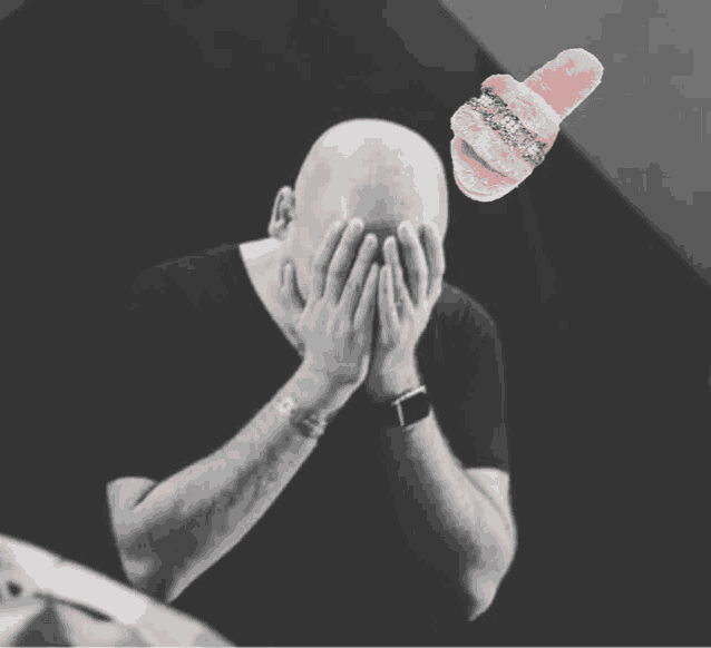 a bald man covering his face with his hands and a pink slipper with rhinestones on it