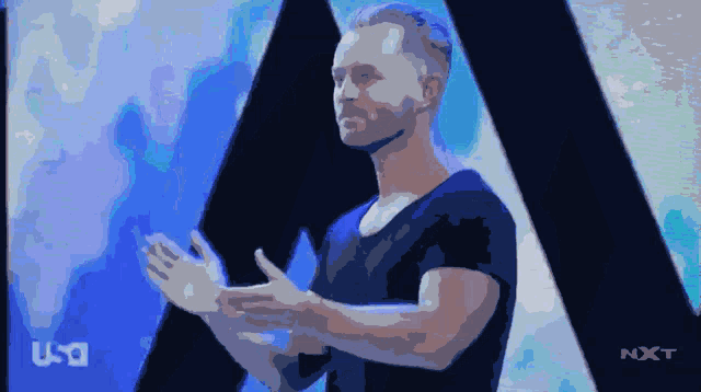 a man is standing in front of a screen that says nxt on it