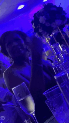 a woman sits at a table with a glass of champagne in front of her