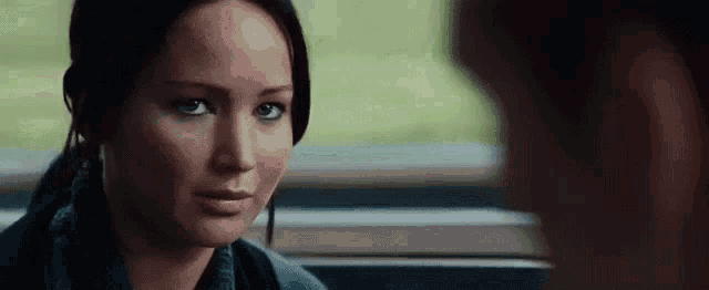 a woman is sitting next to a man on a train and looking at him with her eyes closed .