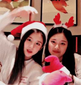 two girls wearing santa hats and antlers pose for a photo