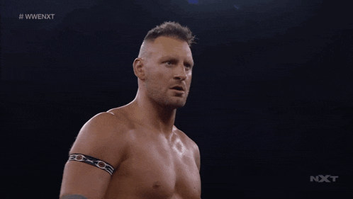 a shirtless wrestler stands in front of another wrestler with the hashtag #wwe nxt on the bottom right