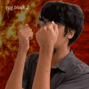 a man wearing glasses holds his fist up in front of a fire background with the words rpg block 2 below him
