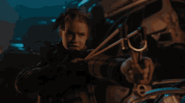 a little girl is holding a slingshot in her hands in a dark room .