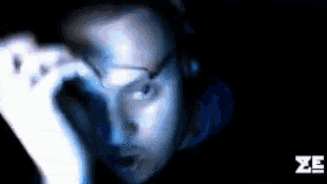 a man wearing glasses and headphones looks at something in the dark .