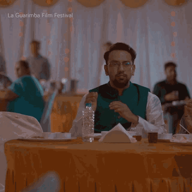 a man sitting at a table with a bottle of water in front of him