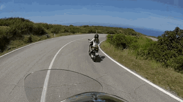 a woman is riding a motorcycle down a road with a helmet on