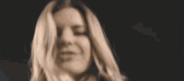 a woman with long blonde hair is smiling with her eyes closed