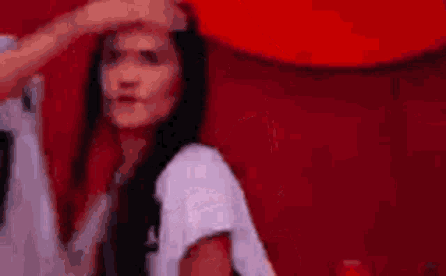 a woman with long black hair is being touched by a man 's hand on her forehead .
