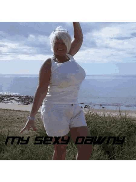 a woman in white shorts and a white tank top stands in front of the ocean with the words " my sexy dawn " below her