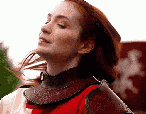 a woman with red hair is wearing a red and white armor .