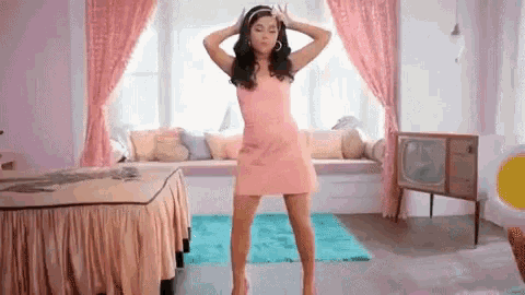 a woman in a pink dress is dancing in a room with pink curtains .