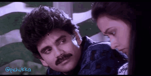 a man with a mustache and a woman looking at each other in a movie