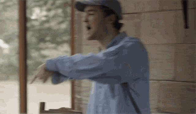 a man wearing a baseball cap and a blue shirt is pointing at something .