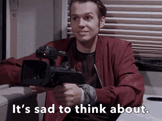 a man holding a camera with the words it 's sad to think about