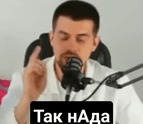 a man is sitting in front of a microphone with his eyes closed and making a funny face .