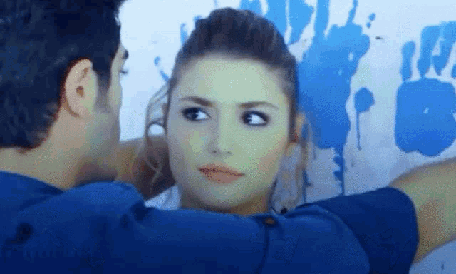 a man and a woman are looking at each other in front of a wall that says ' a ' on it