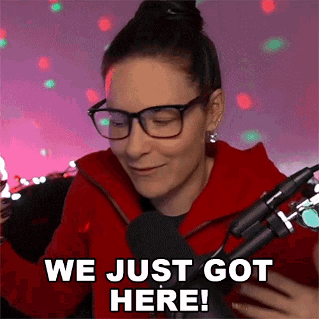 a woman wearing glasses is sitting in front of a microphone and says " we just got here "