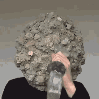 a person is holding a hammer in front of their face .