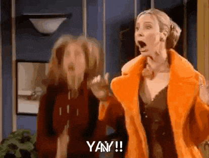 two women are standing next to each other in a room with their mouths open and one of them is wearing an orange fur coat .