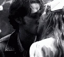 a man and a woman kissing in a black and white photo .