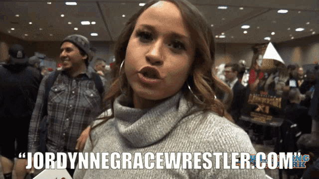 a woman in a grey sweater says jordynegracewrestler.com on the bottom