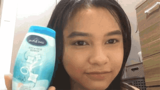 a young girl is holding a bottle of shampoo that says soft & moisture