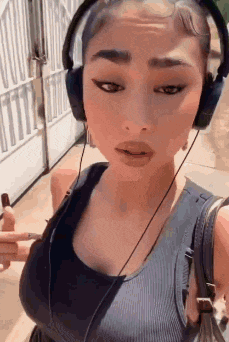 a woman wearing headphones is standing in front of a building .