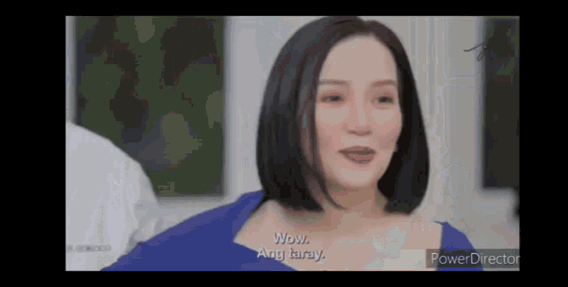 a woman in a blue dress is talking to a man in a video .