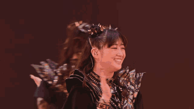 a girl with spikes in her hair is smiling in front of two other girls