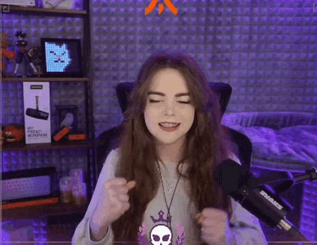a woman is singing into a shure microphone while wearing a skull necklace .