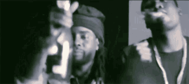 two men are standing next to each other in a dark room .
