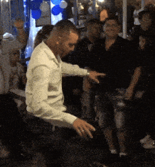 a man in a white shirt is dancing in a crowded room