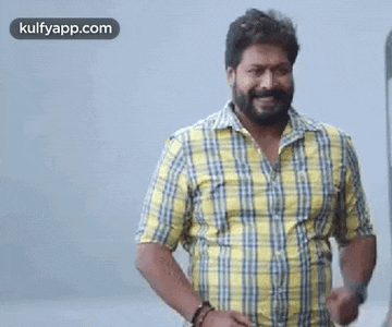 a man with a beard is wearing a yellow and blue plaid shirt and dancing .