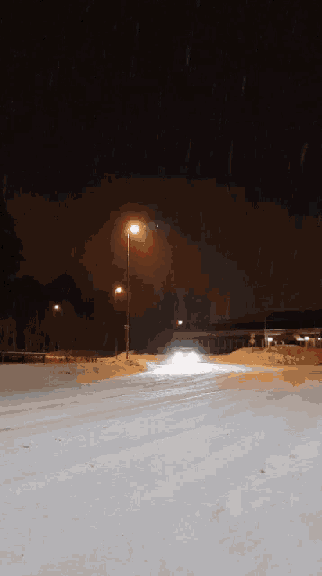 a snowy street at night with a street light in the background