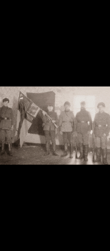 a group of soldiers are standing next to each other holding a flag .
