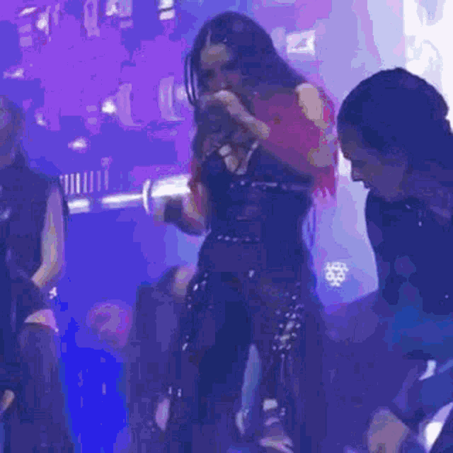 a woman in a red top and black pants is dancing on a stage in a dark room .