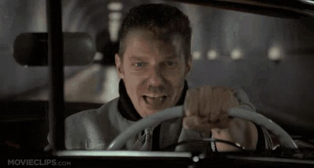 a man is driving a car with movieclips.com written on the bottom