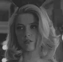 a black and white photo of a woman wearing a bunny ears headband .