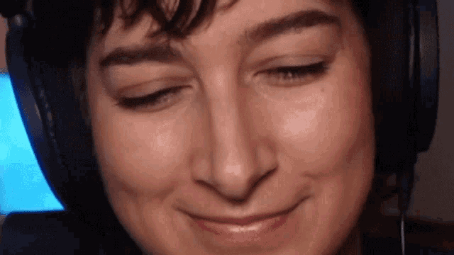 a close up of a woman wearing headphones and making a funny face .