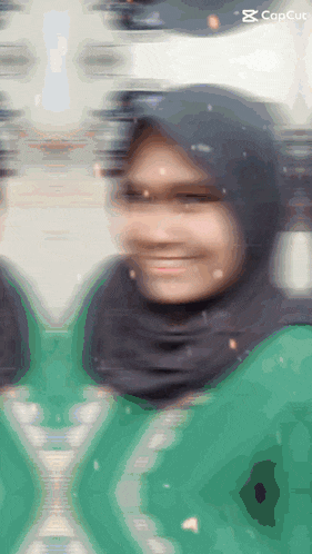 a blurry picture of a woman wearing a hijab and a green shirt with the word concut on the bottom right