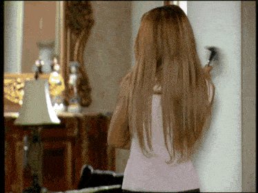 a woman brushes her hair in front of a mirror and lamp