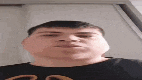 a young man is making a funny face while wearing a black shirt with a mcdonald 's logo on it .
