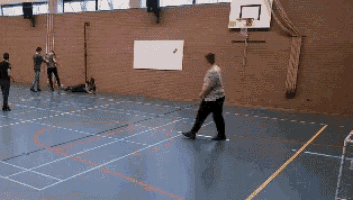 a group of people are playing basketball in a gym with a basketball hoop in the background