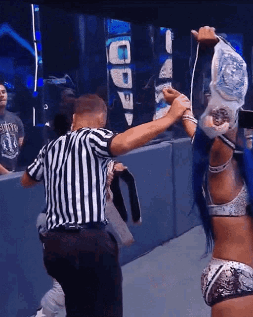 a man in a striped shirt is standing next to a woman in a wrestling ring