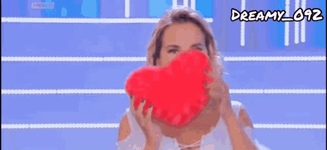 a woman is covering her face with a heart shaped pillow .