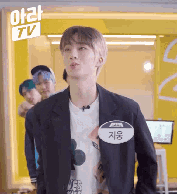 a young man wearing a name tag that says ' tv ' on it is standing in front of a yellow wall .