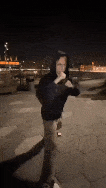 a man in a hooded jacket is walking down a sidewalk at night