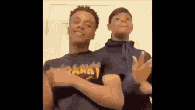 two young men are standing next to each other and making a funny face .